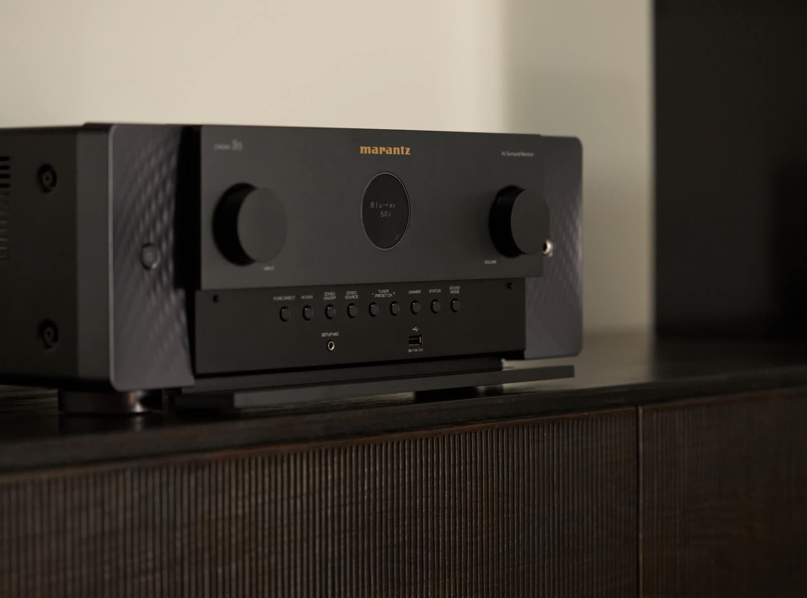 Black Marantz Cinema 50 AV receiver on a ribbed-timber credenza, its display reading Blu-ray.